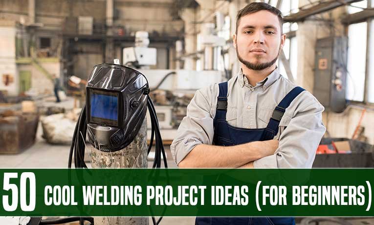 A welder standing with his arms crossed beside a helmet in a workshop